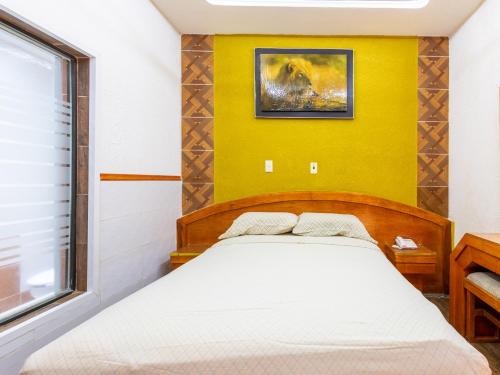 a bedroom with a bed and a yellow wall at Hotel Vista Alegre in Mexico City