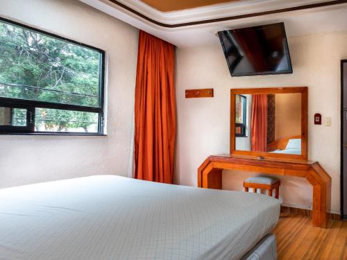 a bedroom with a bed and a mirror and a television at Hotel Vista Alegre in Mexico City
