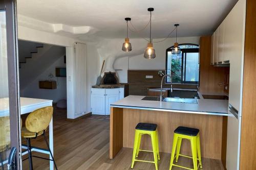 une cuisine avec deux tabourets jaunes à un comptoir dans l'établissement Maison typique corse à 10 min d'Ajaccio et plages, à Alata