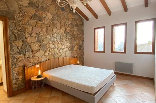 a bedroom with a bed and a stone wall at Maison typique corse à 10 min d'Ajaccio et plages in Alata