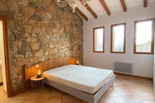une chambre avec un lit et un mur en pierre dans l'établissement Maison typique corse à 10 min d'Ajaccio et plages, à Alata