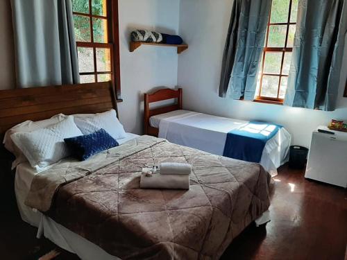 um quarto com 2 camas e 2 janelas em Sitio do Imbuí em Teresópolis em Teresópolis