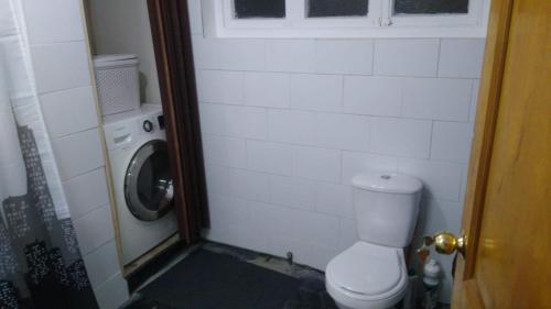 a bathroom with a toilet and a washing machine at Islanet Hostel & Bar in Puerto Montt