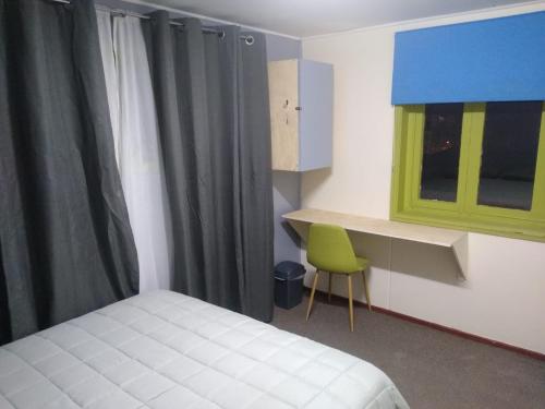 a bedroom with a bed and a green chair at Islanet Hostel & Bar in Puerto Montt