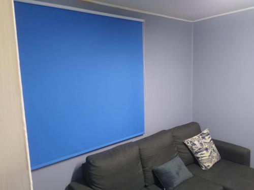 a living room with a black couch and a blue screen at Islanet Hostel & Bar in Puerto Montt