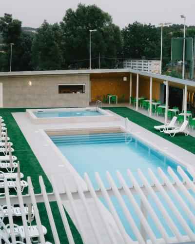 a swimming pool with white chairs next to a building at Hotel La Tavernetta in Campobasso