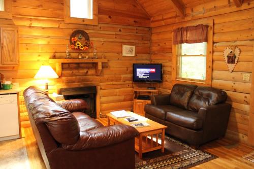 a living room with leather furniture and a television at Country Road Cabins in Hico