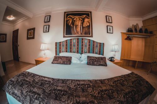 a bedroom with a large bed and a picture of an elephant at Pousada de Charme Vila Natal - Exclusive Boutique in Campos do Jordão