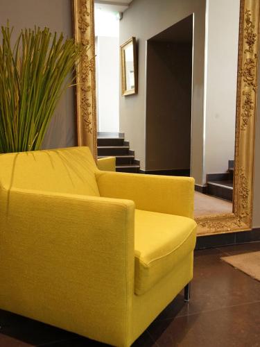 a yellow couch in a living room with a mirror at Hotel De France in Valence