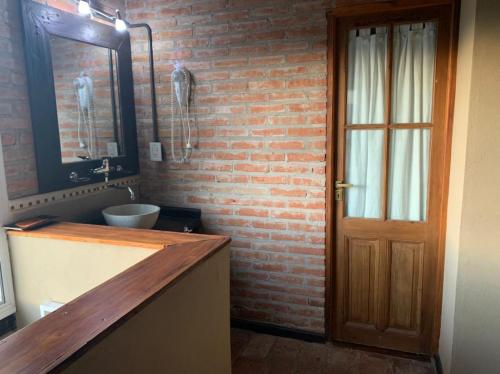 baño con lavabo y pared de ladrillo en Monte Barranco, en Villa Yacanto