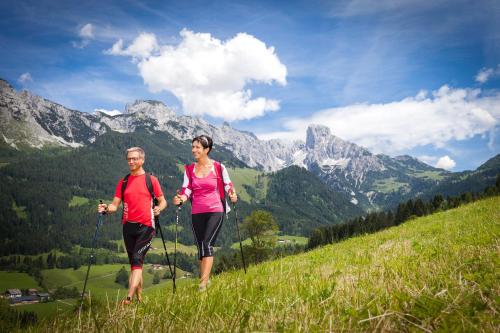 two people walking on a hill in the mountains at Alpenhaus Donnerkogel in Annaberg im Lammertal