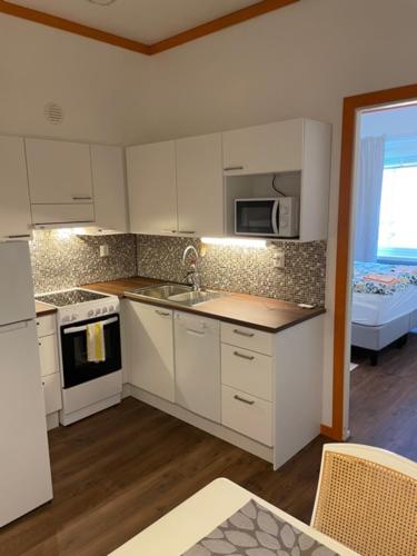 a kitchen with white cabinets and a sink and a microwave at Market place Jakobstad Pietarsaari 53m2 in Pietarsaari