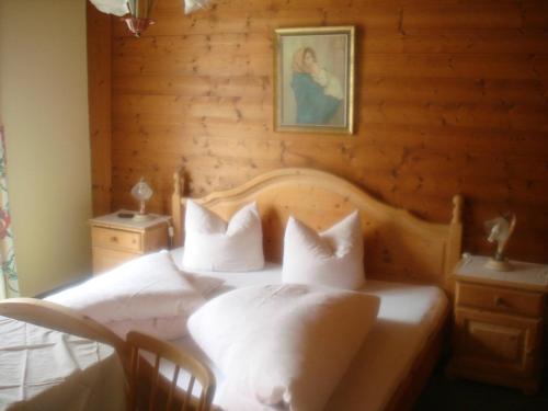 a bedroom with a white bed with a wooden wall at Haus Alpenblick in Pertisau