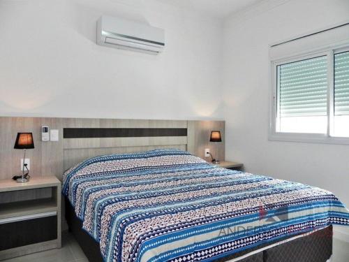 1 dormitorio con 1 cama, 2 mesas y una ventana en 1058 - Praia de Bombinhas locação de temporada, en Bombinhas