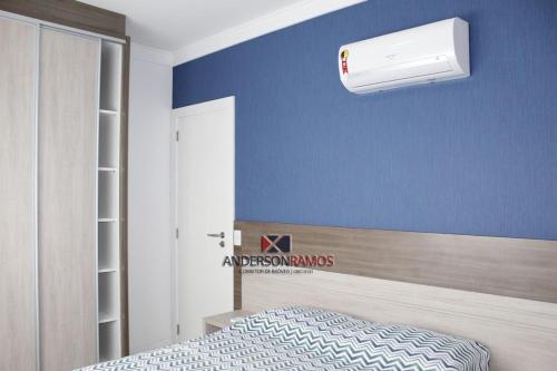 Un dormitorio con una pared azul con una cama y una luz blanca en 1040 - Apartamento para locação em Bombinhas - Residencial Egídio Pinheiro Apto 206 A, en Bombinhas