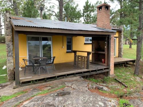 una casita amarilla con terraza y mesa en Monte Barranco, en Villa Yacanto