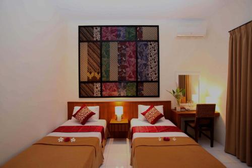 a room with two beds and a desk and a window at Sanur Seaview Hotel in Sanur