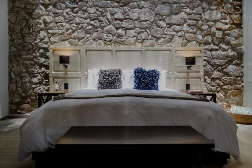 a bedroom with a large bed with a stone wall at Hotel Casa Once in Querétaro