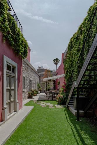 a courtyard with green grass between two buildings at Hotel Casa Once in Querétaro