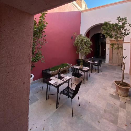 a patio with tables and chairs and a pink wall at Hotel Casa Once in Querétaro