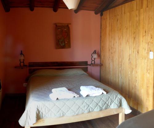 a bedroom with a bed with two towels on it at Rincón Sur Cabañas in Malargüe
