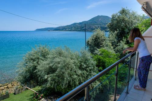 a woman standing on a balcony looking at the water at Sul Mare in Diakopto