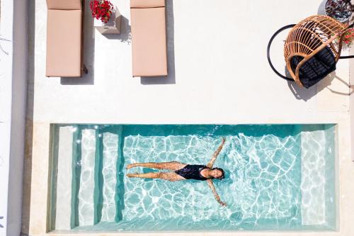 a man swimming in a swimming pool in a swimming pool at Pink Freud Villas Santorini in Oia