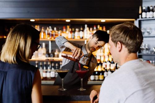 a man making a drink at a bar with a woman at Freycinet Lodge in Coles Bay
