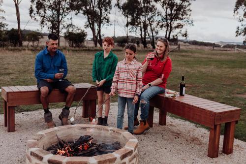 a group of people sitting on benches next to a fire at Wallinga Farmstay Mudgee in Mudgee