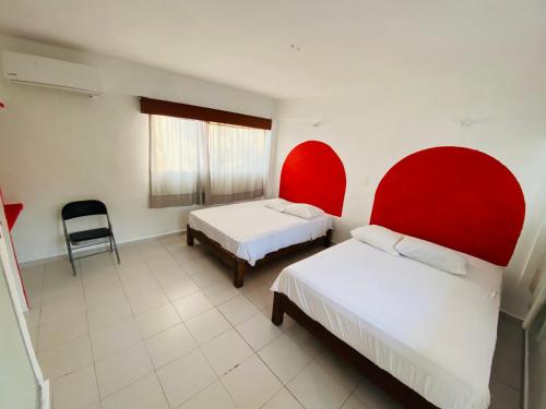 two beds in a room with red headboards at Hotel Maria Bonita Acapulco in Acapulco