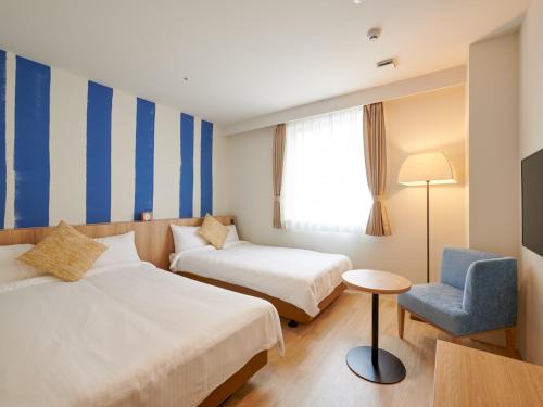 una habitación de hotel con 2 camas y una silla en HOTEL SEABREEZE CORAL, en Isla Miyako