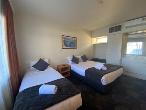 
a hotel room with two beds and two lamps at The Astor Hotel Motel in Goulburn
