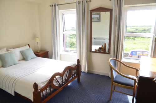um quarto com uma cama, um espelho e uma cadeira em Seaview Guesthouse em Allihies