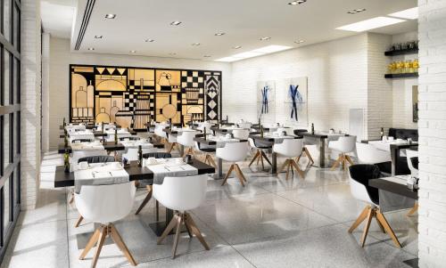 a dining room with tables and white chairs at H10 Art Gallery 4* Sup in Barcelona