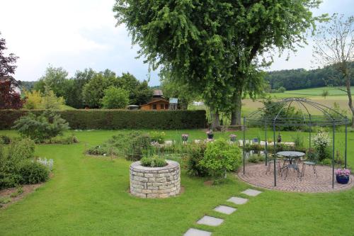 a garden with a greenhouse and a table in the grass at Les Petites Chambres de la Bleue Maison in Coeuve