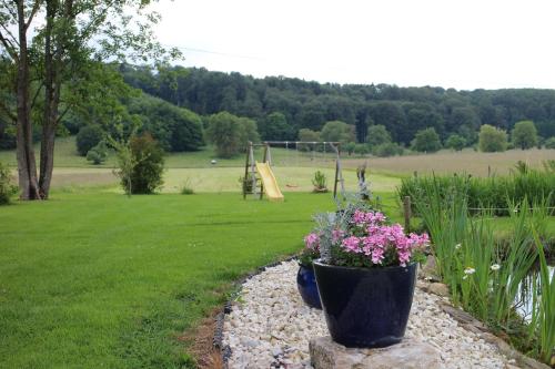 a garden with a park with a playground and flowers at Les Petites Chambres de la Bleue Maison in Coeuve