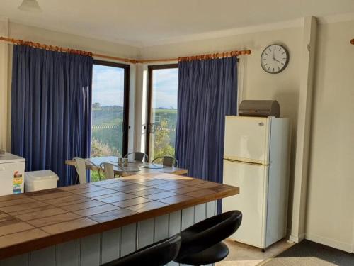 a kitchen with a table and a refrigerator and a clock at Cobden Crest Cottages in Cobden