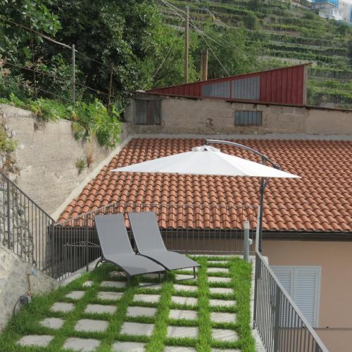a pair of chairs and an umbrella on the grass at Lena Magda B&B in Furore
