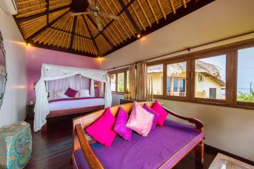 a bedroom with a bed with pink pillows at Life in Amed Beach Hotel in Amed