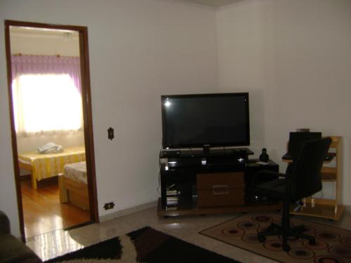 a living room with a flat screen tv and a chair at Apartamento Guarulhos in Guarulhos