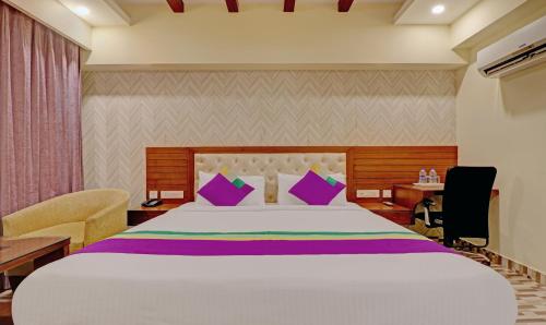 a hotel room with a large bed with purple pillows at Treebo Premium Pearl Avenue Banquets And Lawn in Dehradun