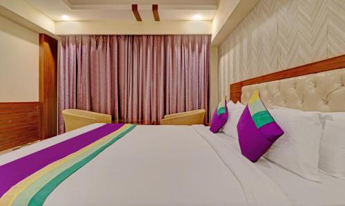 a bedroom with a large bed with colorful pillows at Treebo Premium Pearl Avenue Banquets And Lawn in Dehradun