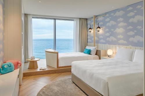 1 dormitorio con 2 camas y vistas al océano en Grand Josun Busan, en Busan