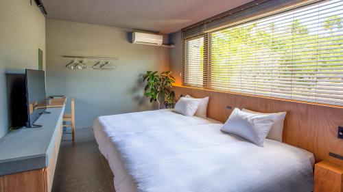 a bedroom with a large white bed with a window at Feliz Villa Suite Kourijima View in Nago