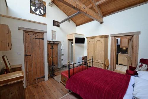 1 dormitorio con cama roja y reloj en la pared en Shed End, in 18th century Lothersdale Mill BD20 8EN en Lothersdale