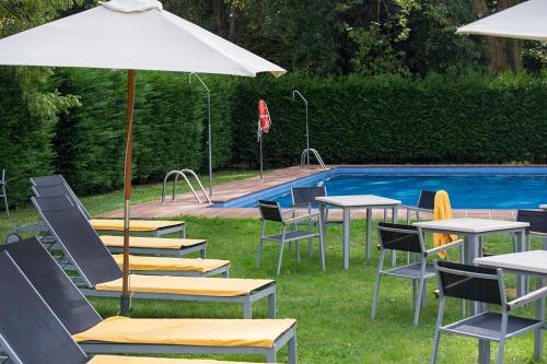 a group of tables and chairs next to a swimming pool at Parador de Limpias in Limpias