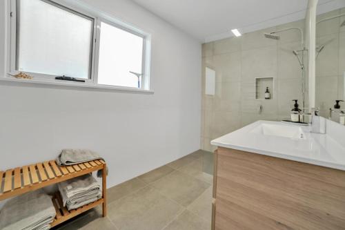 Baño blanco con lavabo y espejo en Beach House on Bentley, en Bridport
