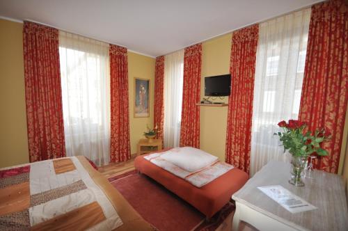 ein Schlafzimmer mit einem Bett, einem Stuhl und Vorhängen in der Unterkunft Hotel Restaurant "Athen" in Münstermaifeld