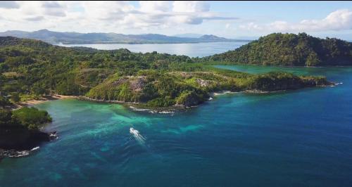 an island in the ocean with a boat in it at Hotel Océan Beach Sakatia in Nosy Be