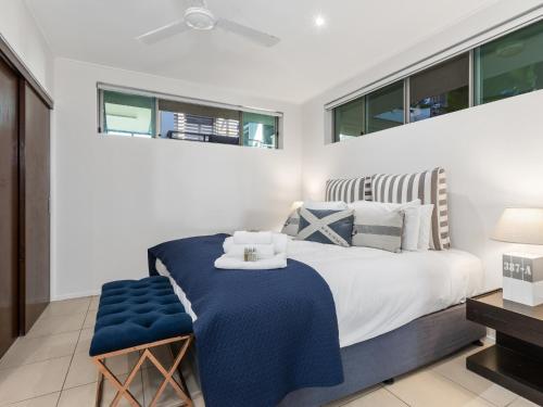 a bedroom with a bed with a blue blanket and windows at Paradiso Resort by Kingscliff Accommodation in Kingscliff